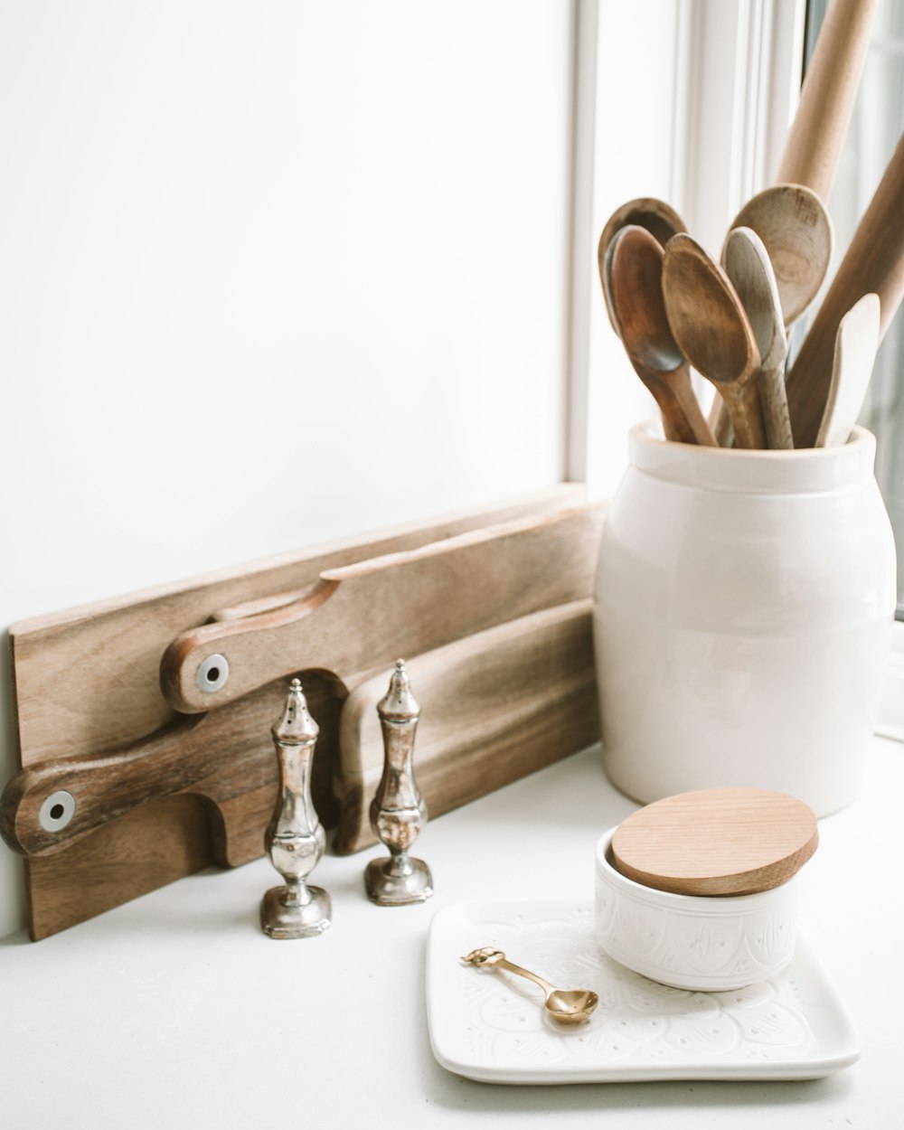 cucchiai di legno marroni su contenitore di ceramica su superficie superiore bianca