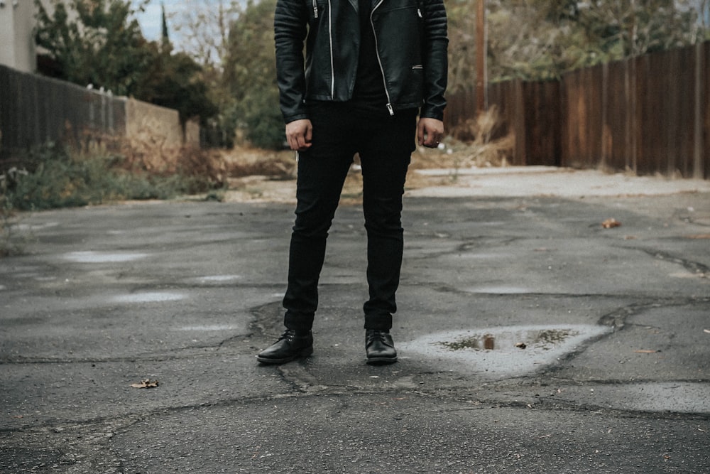 man wearing black pants standing on gray road