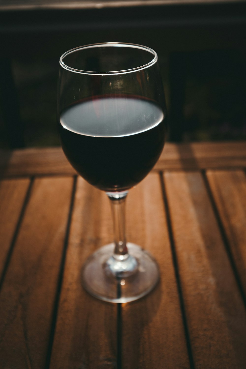 Copa de vino transparente con líquido negro sobre superficie marrón