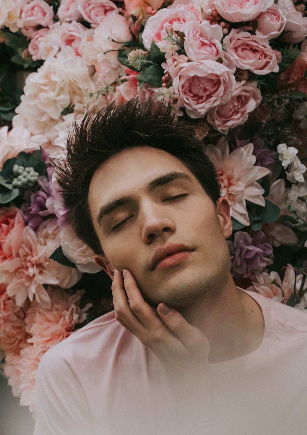 man closing eye beside pink flower