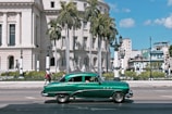 green sedan parks near white building