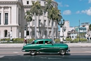 green sedan parks near white building