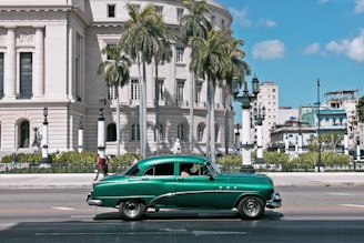 green sedan parks near white building