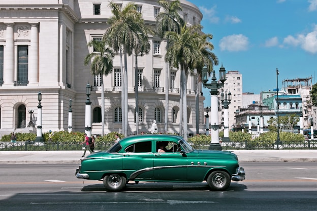 green sedan parks near white building