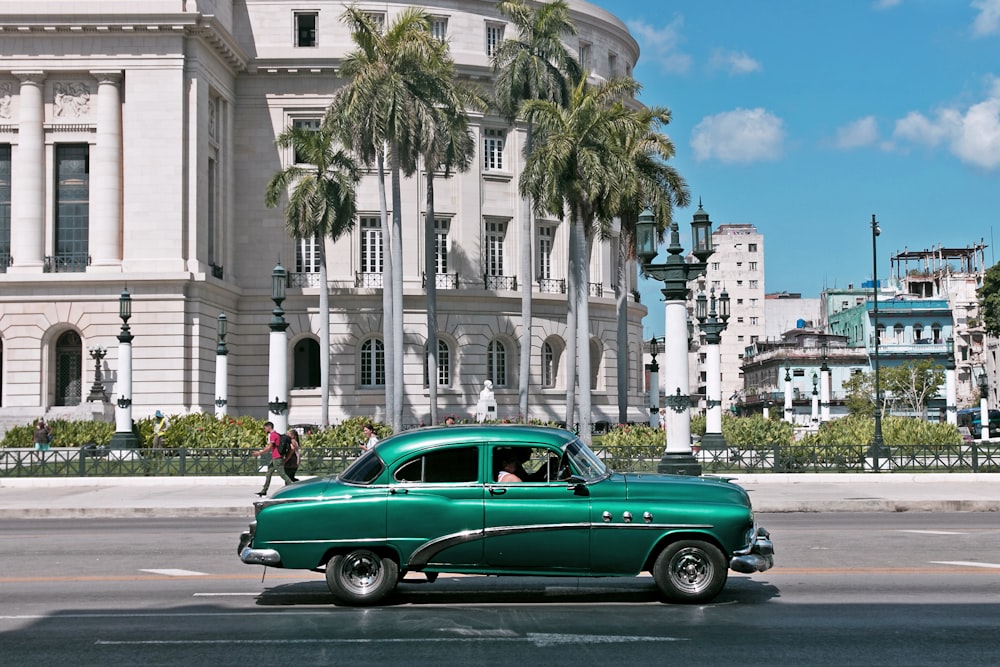 green sedan parks near white building