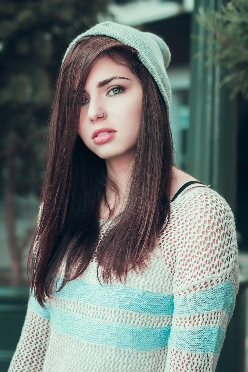 mujer con top de punto blanco y azul de pie frente al árbol