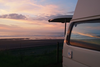 white vehicle parked near ocean during golden hour