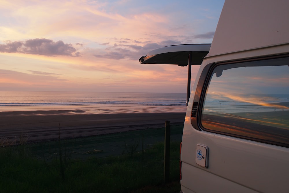 white vehicle parked near ocean during golden hour