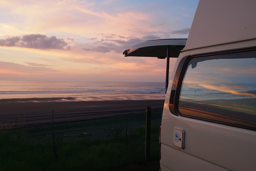 white vehicle parked near ocean during golden hour,
