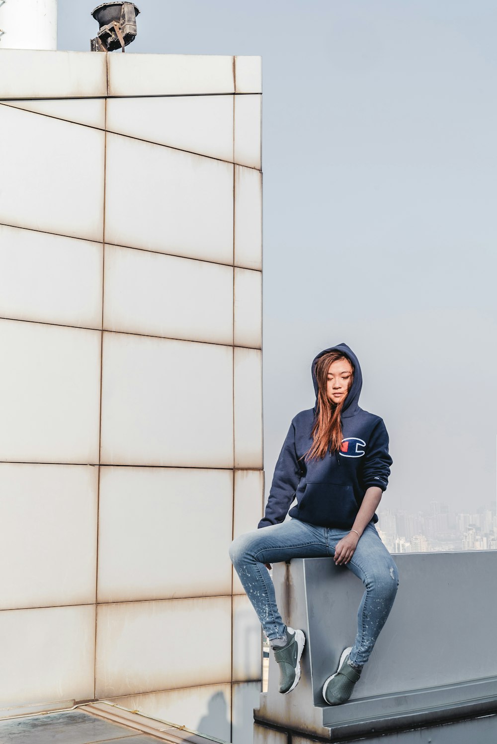 woman sitting on concrete wall on building