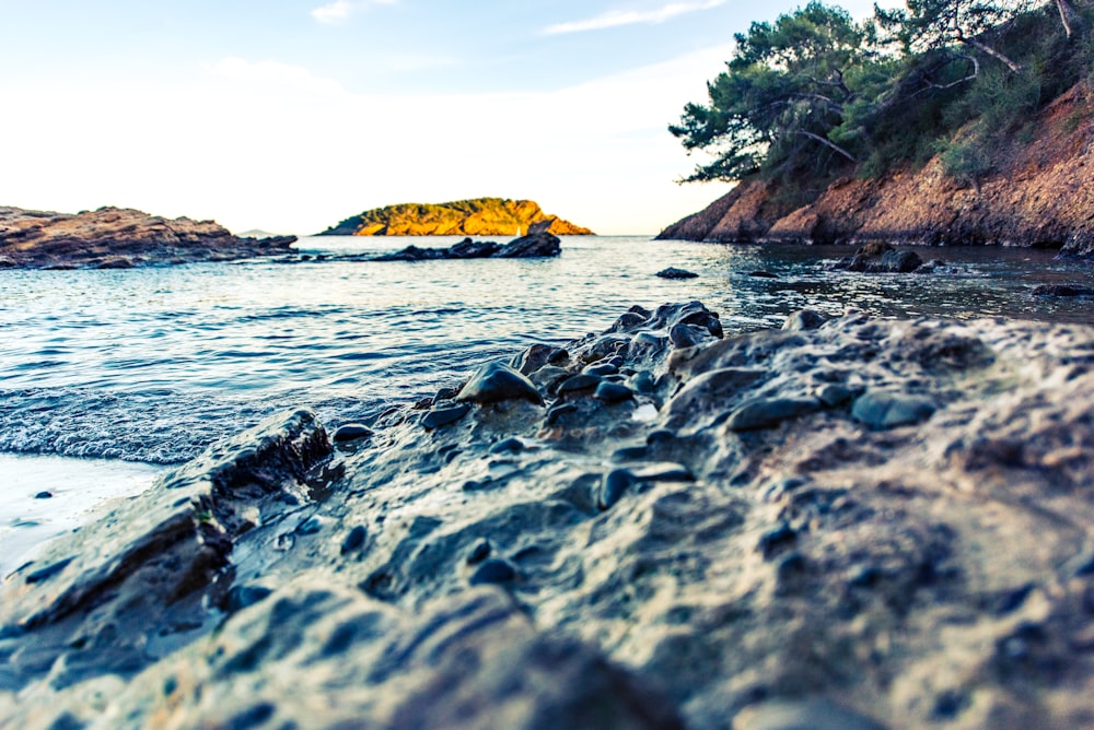 rocks beside body of water and mountains at daytime