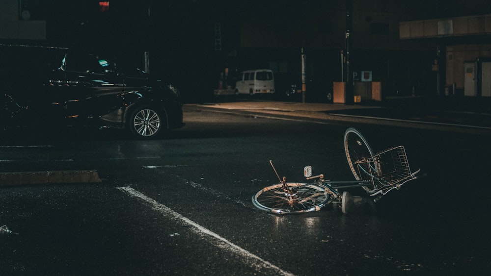 grey bicycle on road near black vehicle at nighttime