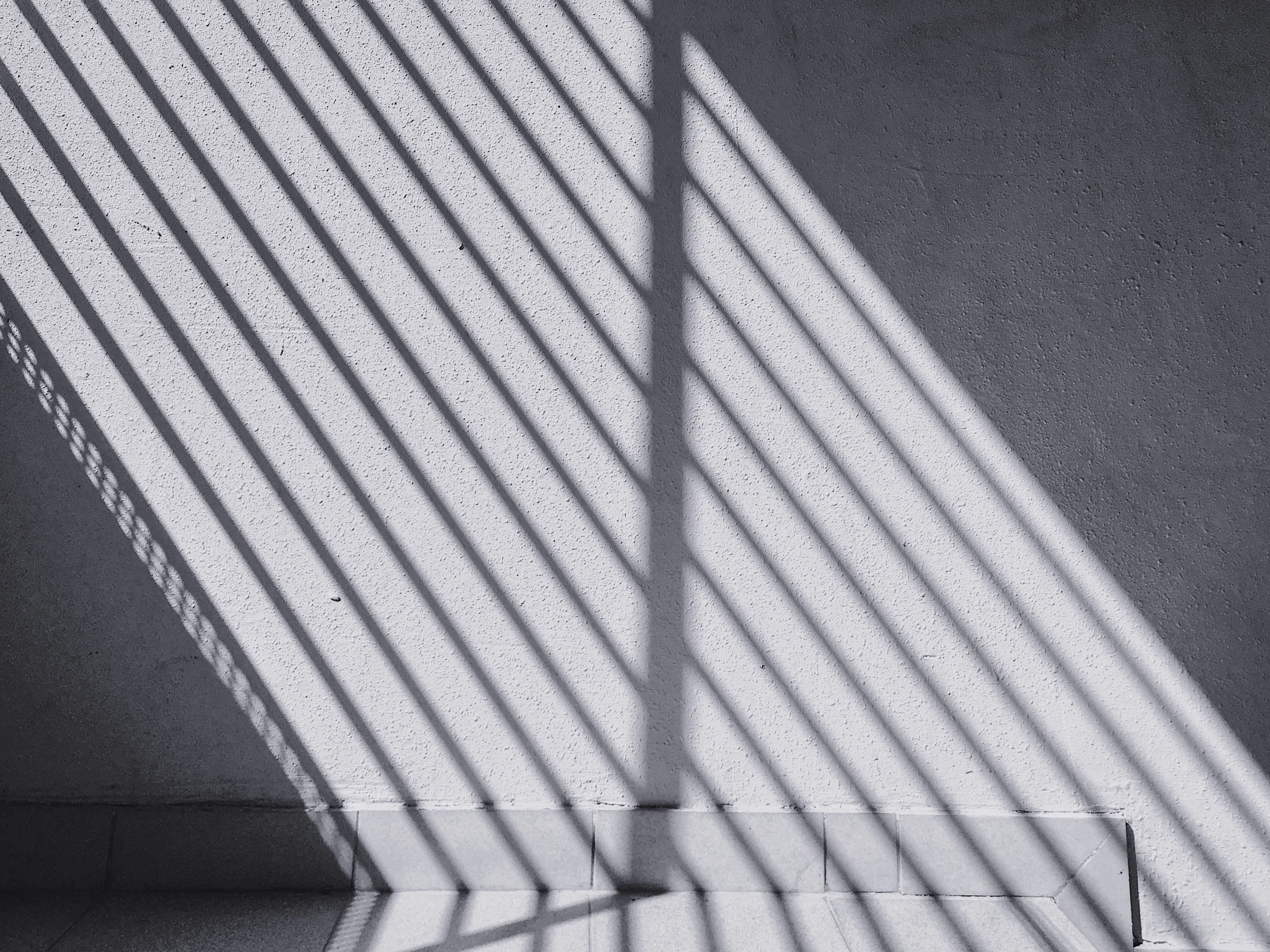 Parallel lines of shadow across a textured wall