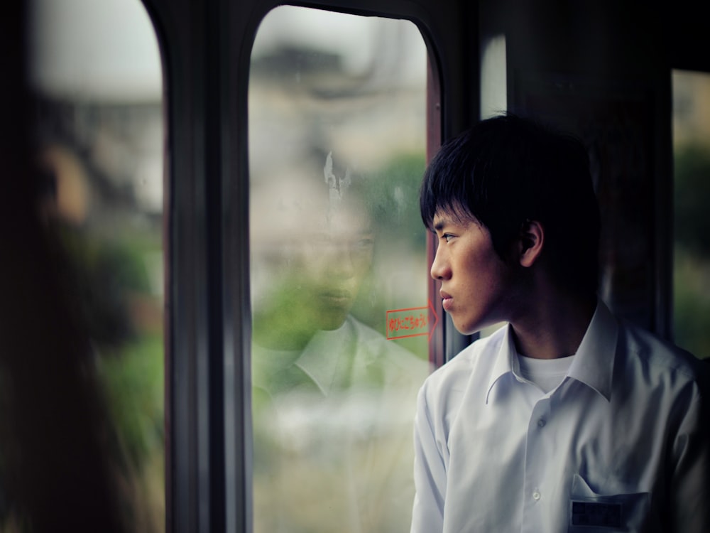 man in dress shirt standing in front of glass door