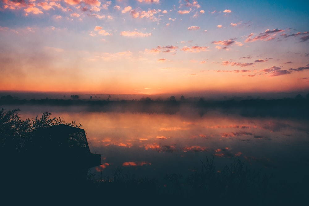 lake under white clouds during golden hour