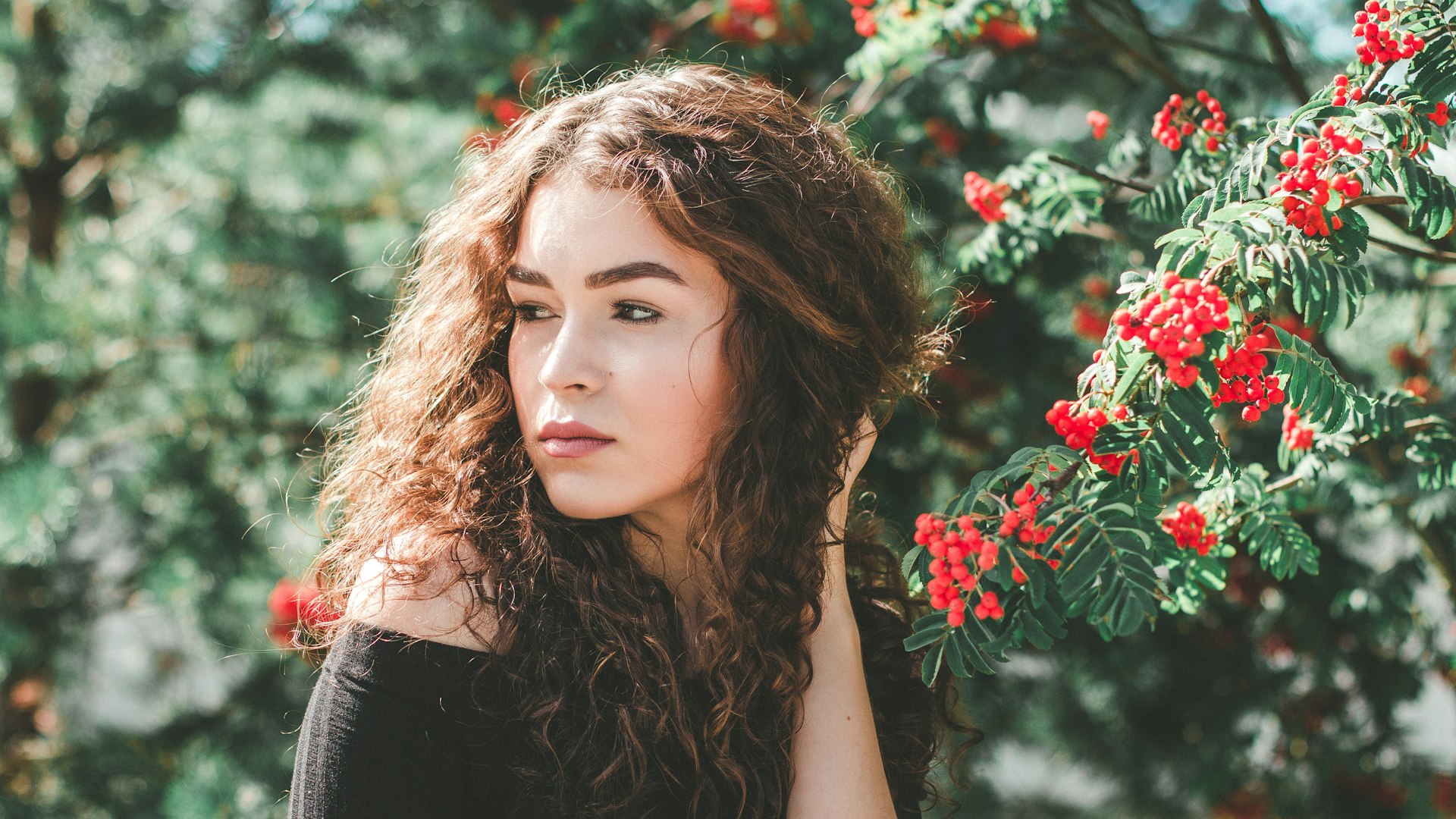 Woman posing near colorful flowers evoking the summer season
