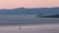 A serene Mediterranean coastline at sunset with a small sailboat gliding quietly on calm waters.