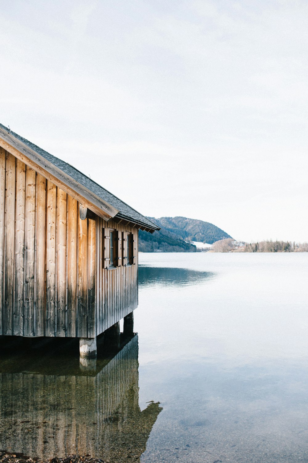 brown wooden house on body of water under gray sky