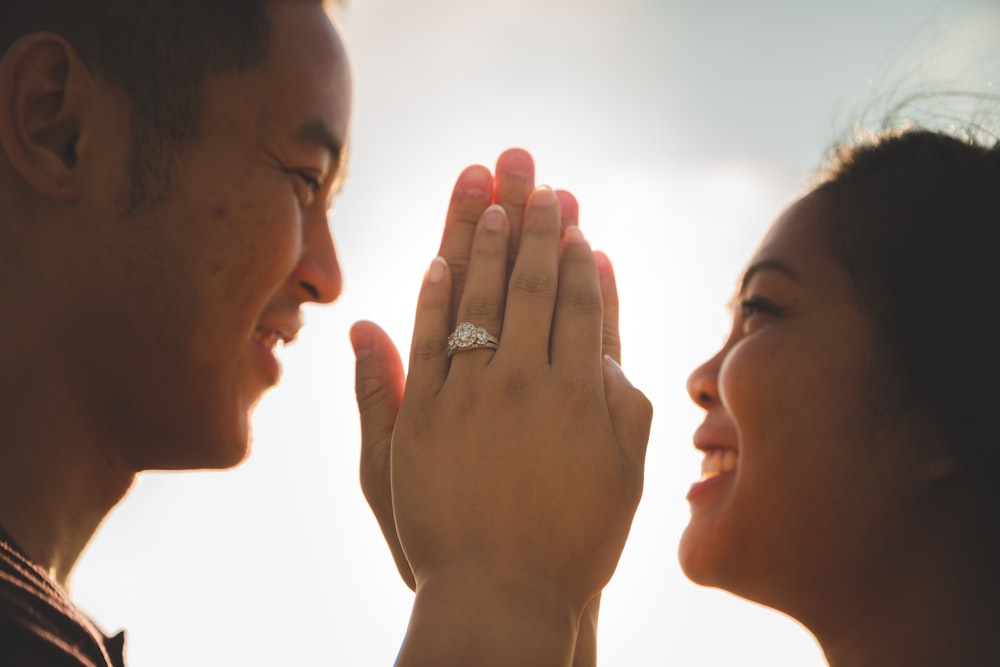 smiling woman and man facing each other while holding palms