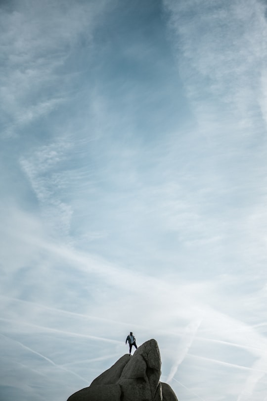 man standing on cliff under white sky in Joshua Tree National Park United States