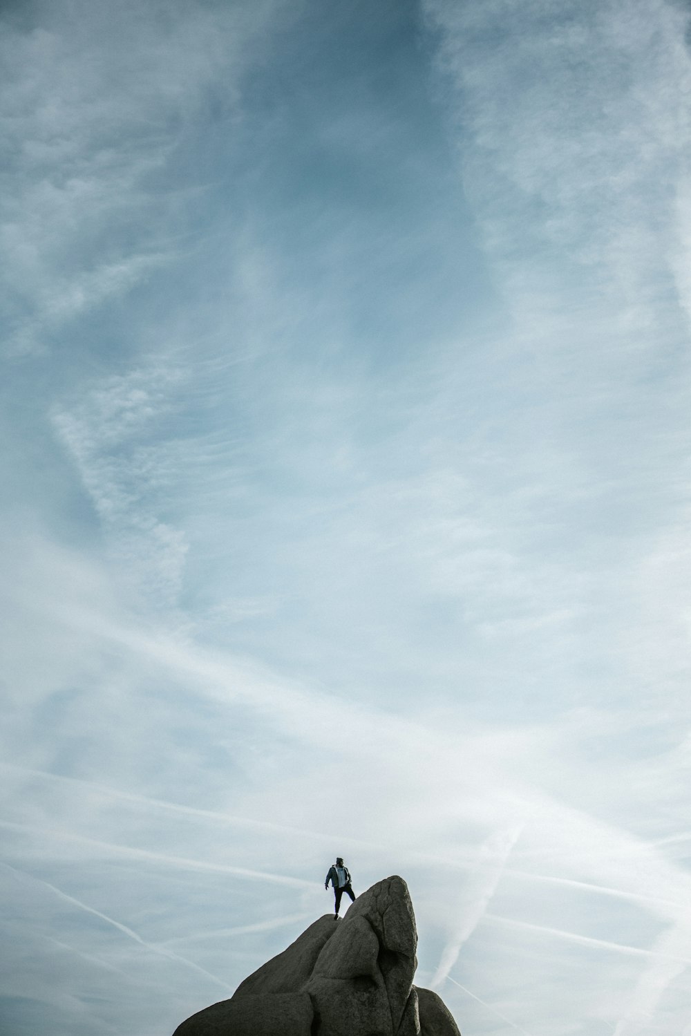 man standing on cliff under white sky