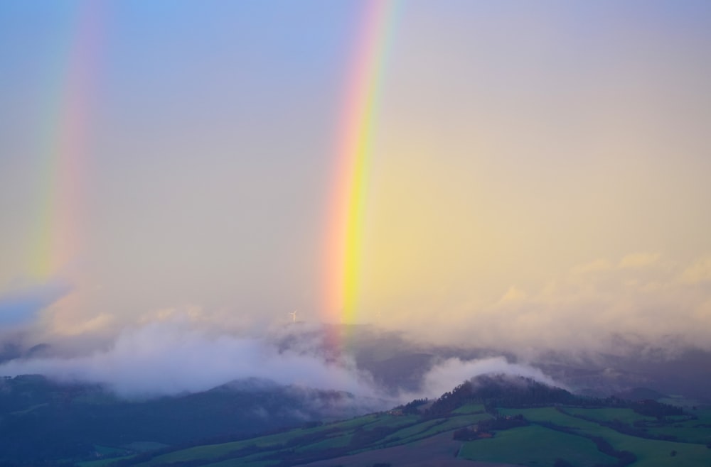 霧に覆われた茶色の山に虹