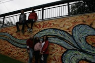 Kayla Kua posing with her band in front of a colorful mural in the Dallas-Fort Worth metroplex.