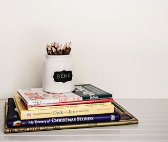 white ceramic pencil organizer on top of stack of books