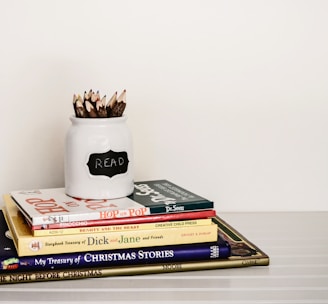 white ceramic pencil organizer on top of stack of books