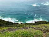 A scenic cliffside view overlooking turquoise ocean waters and rocky formations.