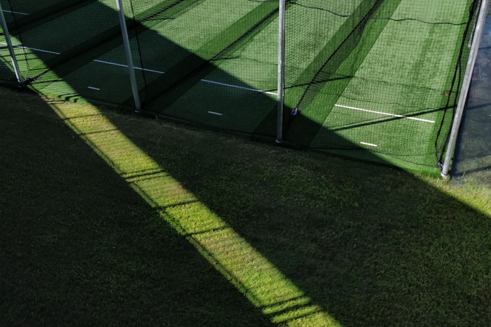 green grass field with black mesh net fence