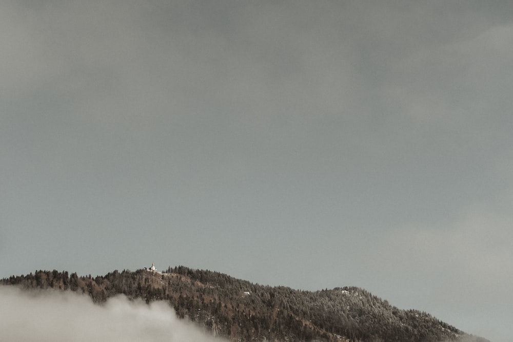 a mountain covered in fog and clouds under a cloudy sky