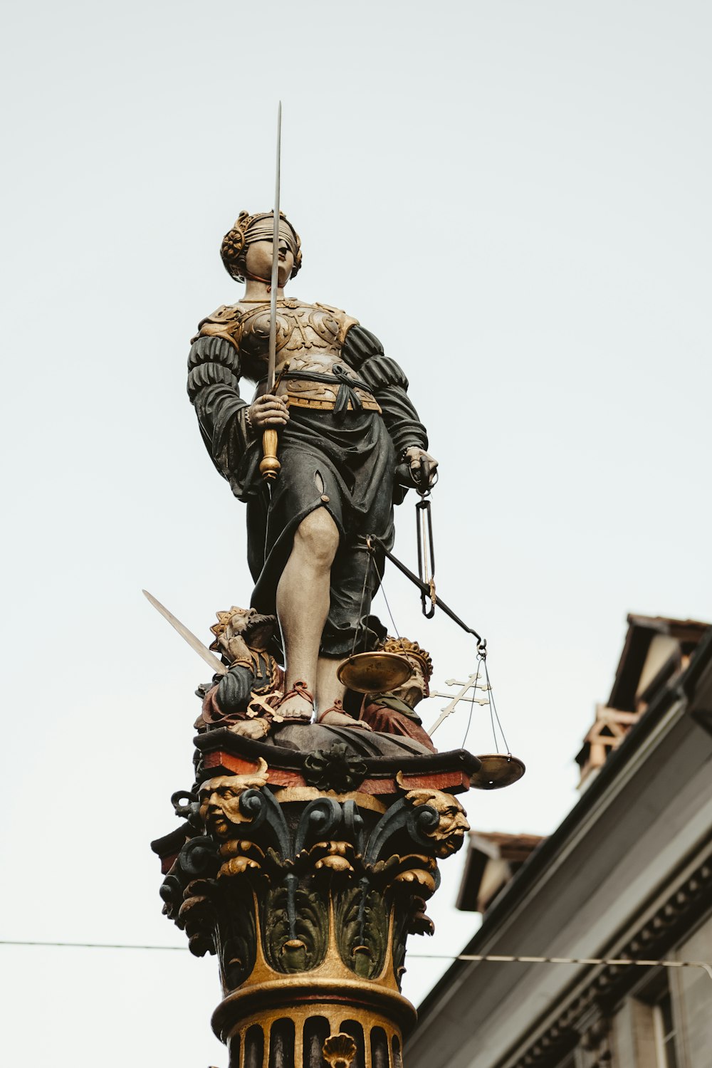 mujer sosteniendo la espada y la estatua de la balanza bajo el cielo blanco