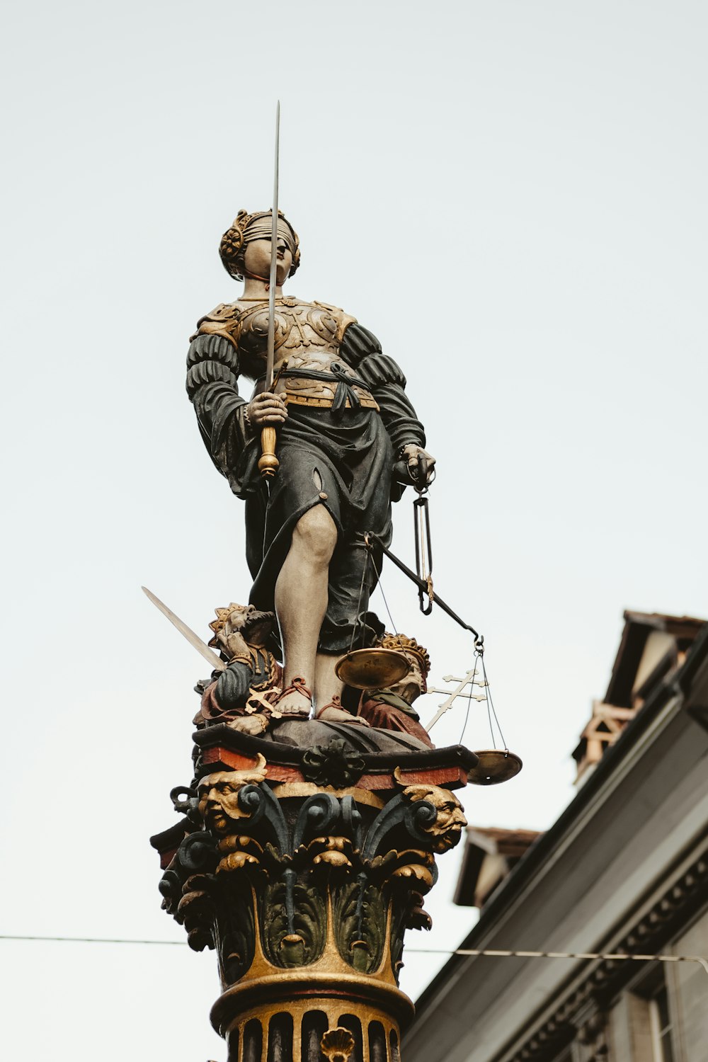 白い空の下で剣と天秤の像を持つ女性
