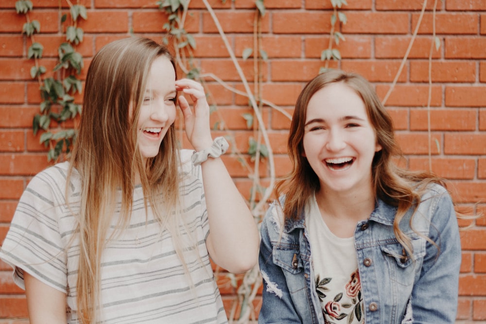 Dos mujeres sonriendo de pie cerca de la pared