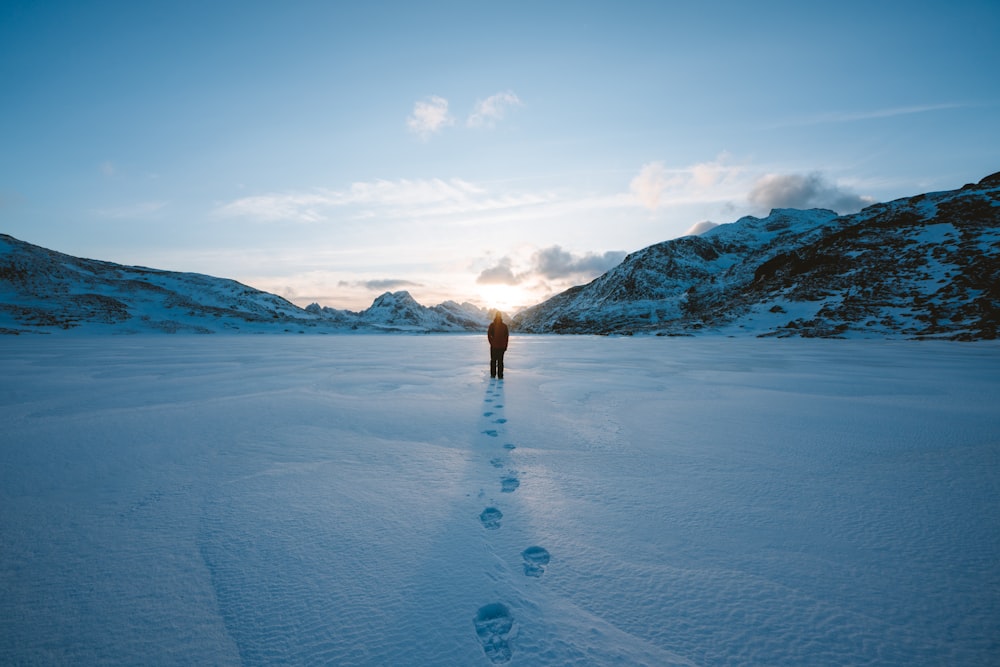 person walking on snow field leaving foot prints