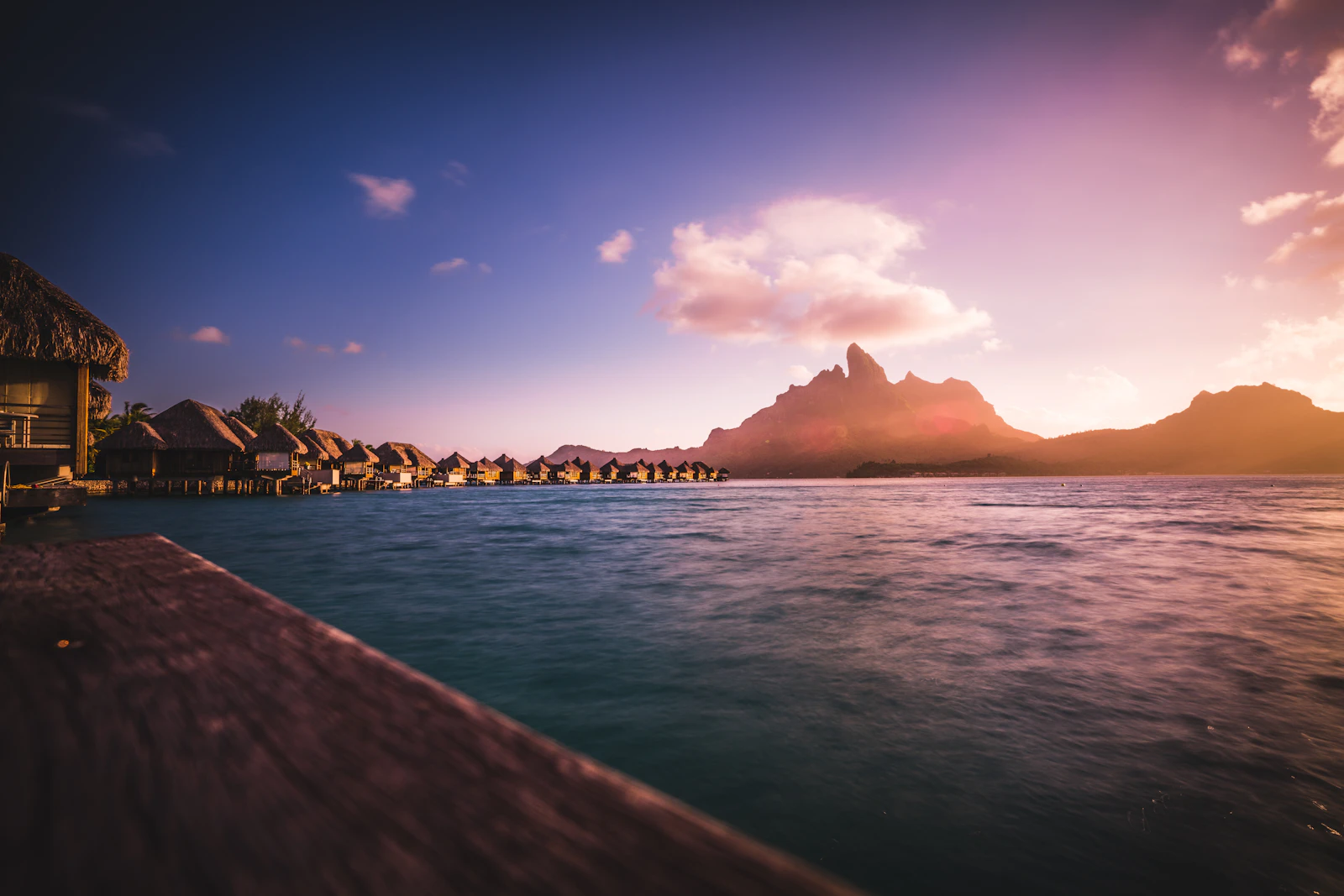 Overwater bungalows on the Bora Bora lagoon at dusk, Mount Otemanu behind