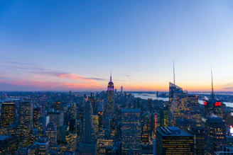 A panoramic cityscape at dusk showcasing modern corporate buildings with warm ivory lighting.