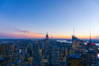 A panoramic global city skyline at dusk with financial district lights.