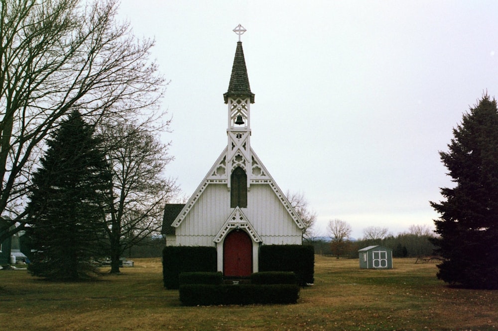 white and red church between trees