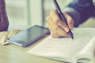 a person writing on a piece of paper with a pen