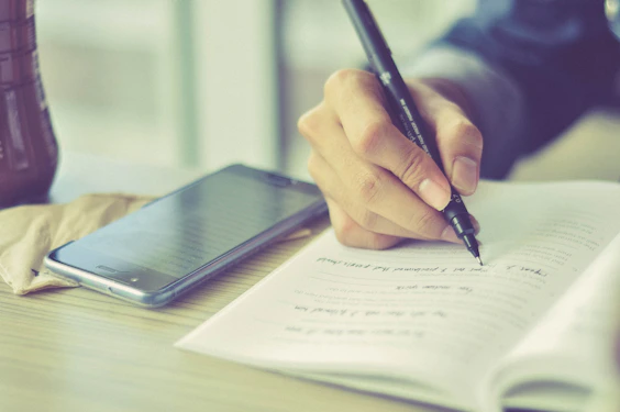 a person writing on a piece of paper with a pen