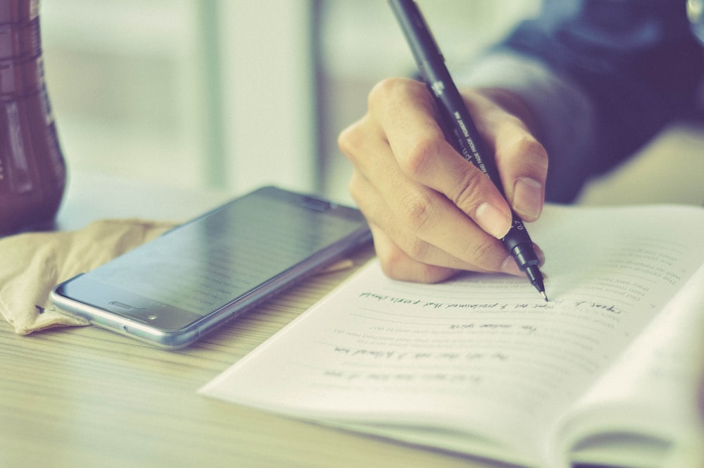 a person writing on a piece of paper with a pen