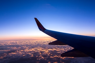 A sleek airplane soaring above fluffy clouds at sunset, symbolizing a smooth journey.