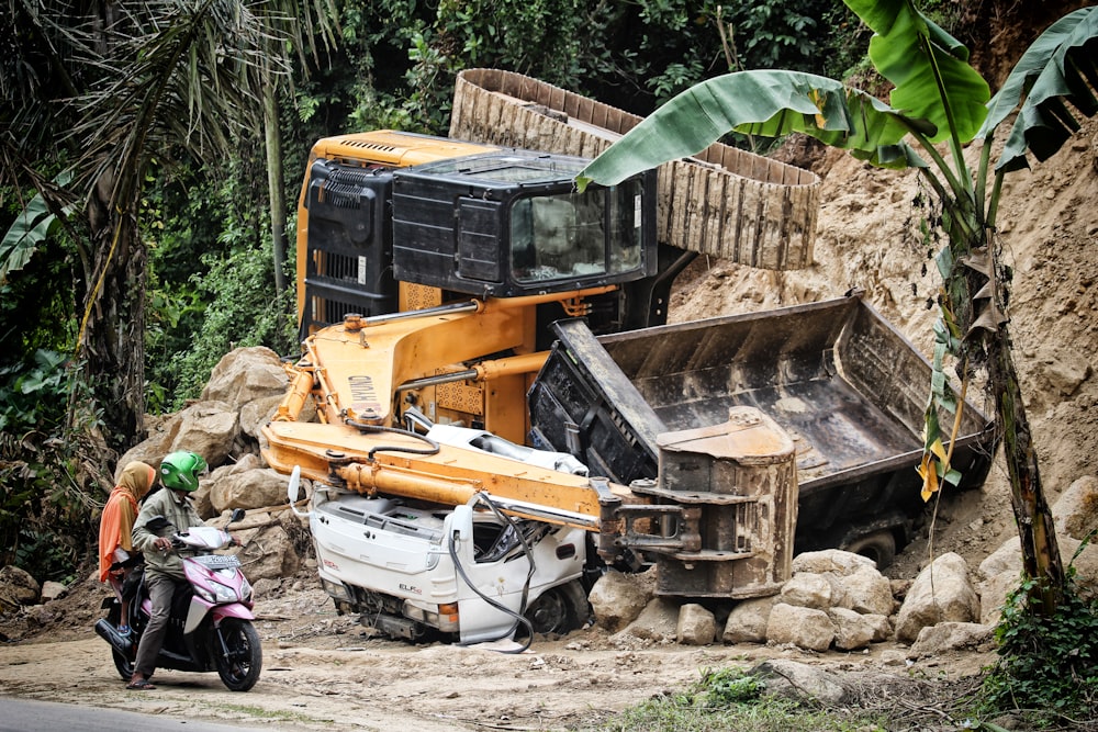 two people riding motorcycle looking at the excavator accident