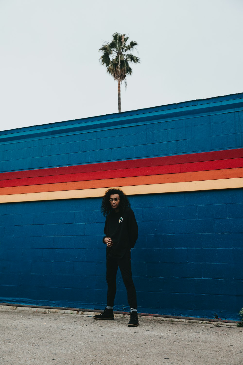 man standing beside blue concrete wall