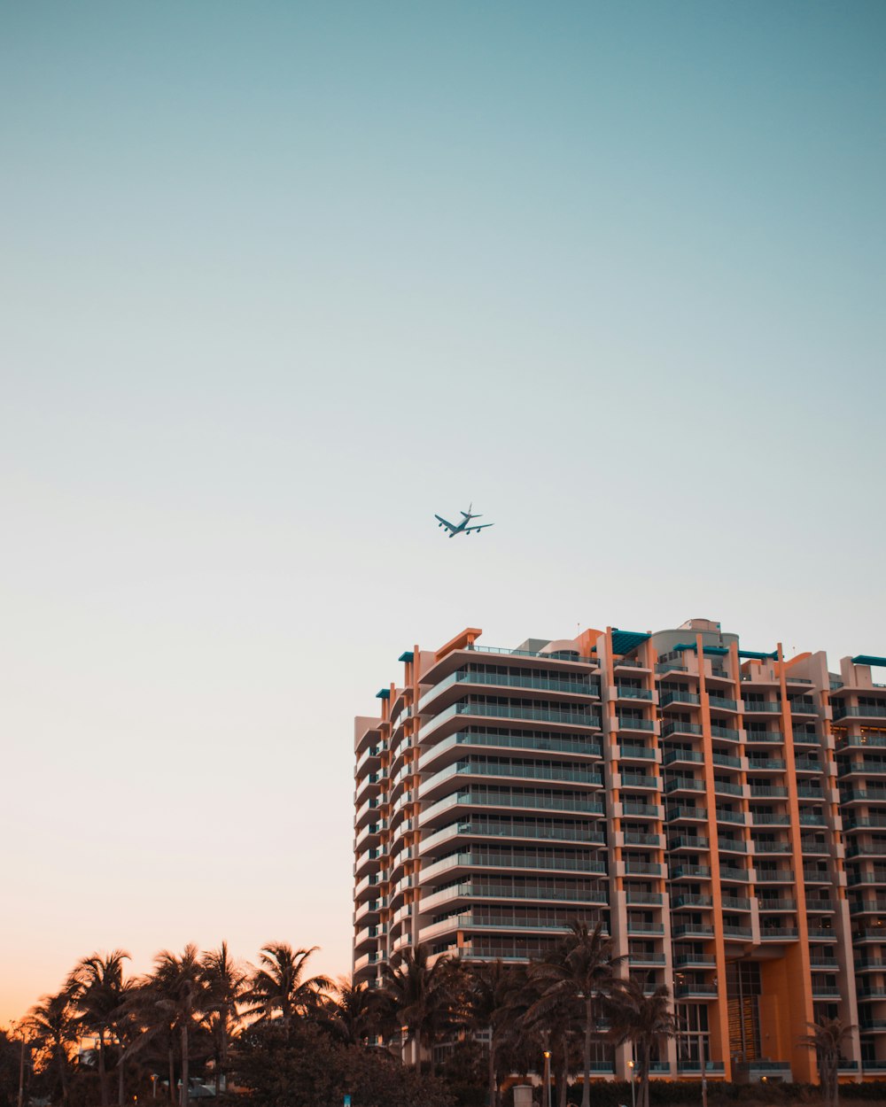 gray airplane above concrete high-rise building