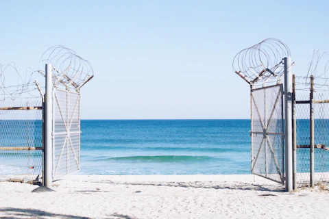photography of white opened gate with barb wire