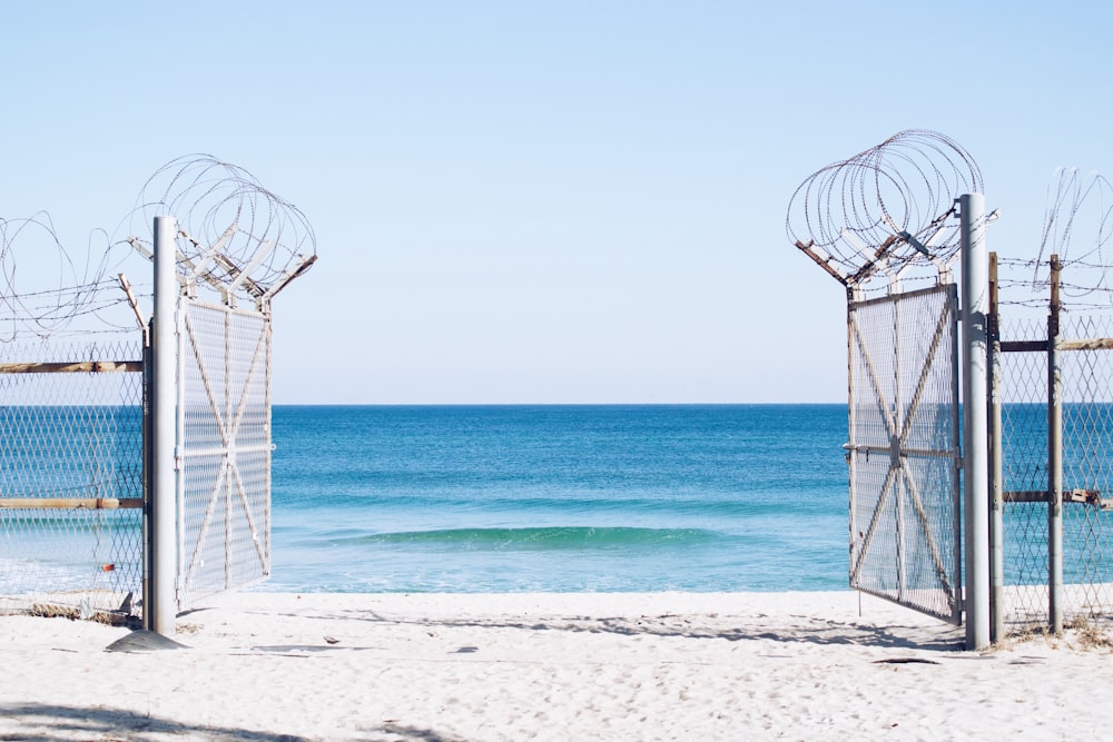 photography of white opened gate with barb wire