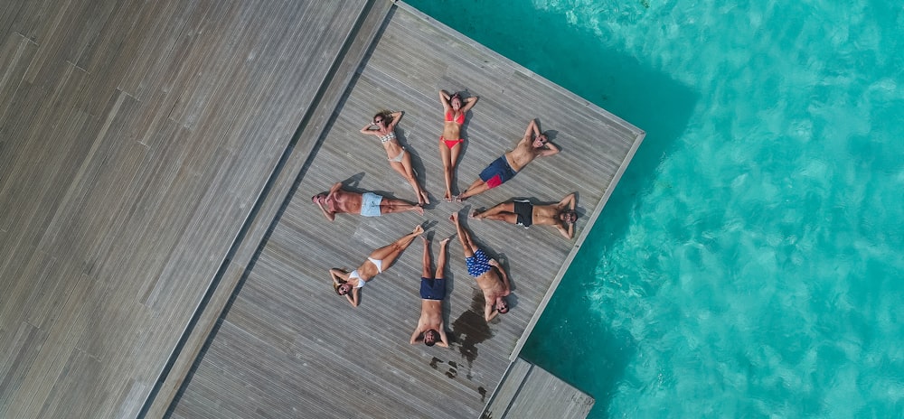 aerial photography of people lying on dock forming circle